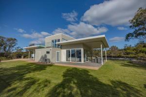 a house with a large lawn in front of it at Baileys Beach House in Binalong Bay