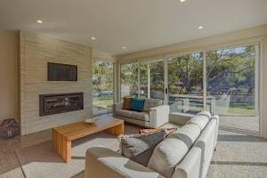 a living room with a couch and a fireplace at Baileys Beach House in Binalong Bay