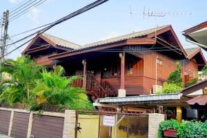 een houten huis met een hek ervoor bij Huan Kawin Est.58 Lanna Home & Collection in Chiang Rai