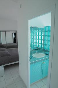 a bathroom with a blue sink and a bed at Les Arcades in Porto-Vecchio