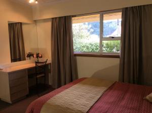 1 dormitorio con cama, escritorio y ventana en AAA Marlin Motel en Picton