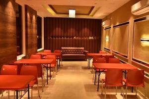 a dining room with red tables and a bench at Hotel Oscar in Amritsar