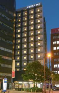 a tall building with lights on in a city at Sotetsu Fresa Inn Osaka Namba in Osaka