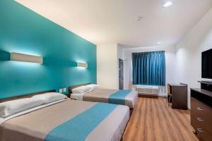 a hotel room with two beds and a flat screen tv at Motel 6-Channelview, TX in Channelview