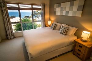 ein Schlafzimmer mit einem Bett und einem großen Fenster in der Unterkunft Villa Jasper Bay of Fires in Binalong Bay