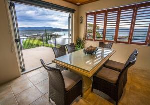 ein Esszimmer mit einem Tisch und Stühlen sowie einem Balkon in der Unterkunft Villa Jasper Bay of Fires in Binalong Bay