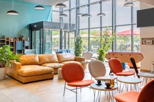 a lobby with a couch and tables and chairs at BEST WESTERN HOTEL DIJON QUETIGNY in Quétigny