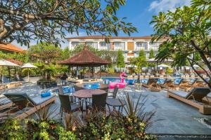 a resort with a pool with chairs and a table at Kuta Beach Club Hotel in Kuta