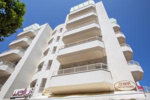 a tall white building with a sign on it at Wally Residence in Rimini