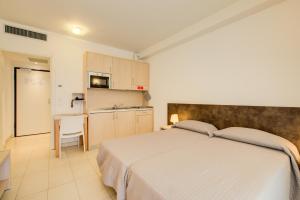 a bedroom with a large bed and a kitchen at Wally Residence in Rimini