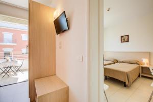 a room with a bed and a television on a wall at Wally Residence in Rimini
