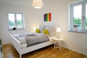 a white bedroom with a bed and two windows at Ferienwohnung Bergmaier in Bad Birnbach