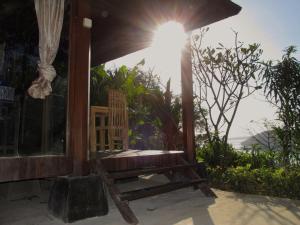 un banco de madera sentado fuera de una casa con el sol en Twin Island Villas & Dive Resort en Nusa Lembongan