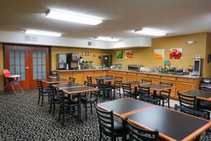 a restaurant with tables and chairs and a kitchen at Quality Inn & Suites Watertown in Watertown