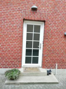 a red brick building with a white door and stairs at Like home Bed & Breakfast in Varde