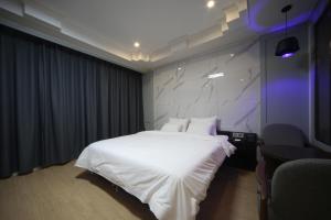 ein Schlafzimmer mit einem weißen Bett und einem lila Licht in der Unterkunft Bestie Hotel in Busan