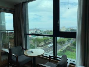 a room with a table and chairs and a large window at Lemain Hotel in Jeju