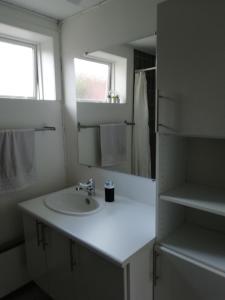 La salle de bains blanche est pourvue d'un lavabo et d'un miroir. dans l'établissement Like home Bed & Breakfast, à Varde