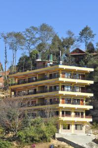 a yellow building on top of a hill with trees at Hotel Valley View Inn in Nagarkot
