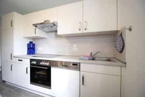 a kitchen with white cabinets and a sink at Ferienhof-Friedenshof-Gerste in Vollerwiek