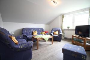 a living room with blue chairs and a table and a tv at Ferienhof-Friedenshof-Gerste in Vollerwiek