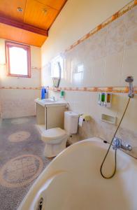 La salle de bains est pourvue d'une baignoire, de toilettes et d'un lavabo. dans l'établissement Bali Spring Cottages, à Ubud