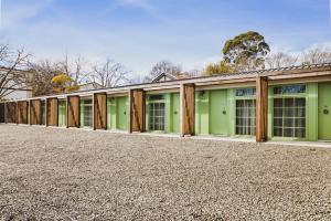 una fila de edificios verdes con ventanas tapiadas en The Bowral Hotel, en Bowral