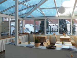 a conservatory with a glass roof with chairs and tables at Hotel Deutscher Kaiser in Travemünde