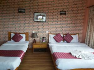 two beds in a room with a brick wall at Hotel Valley View Inn in Nagarkot