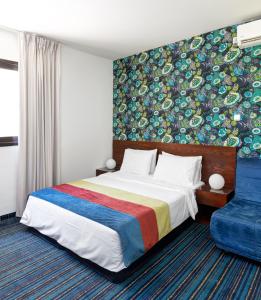 een slaapkamer met een bed en een kleurrijke muur bij Mizpe Yam Boutique Hotel in Netanya