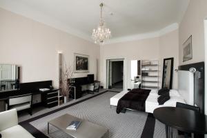 a white bedroom with a bed and a chandelier at Old Town Square Residence by Emblem in Prague