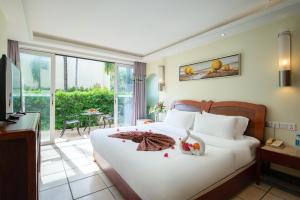 a bedroom with a large white bed and a balcony at Palm Beach Resort & Spa in Sanya