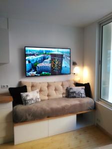 a living room with a couch with a tv on the wall at Avec CLIMATISEUR appartement DESIGN vous propose, un appartement 2 chambres et salon, 3 appartements une pièce, NETFLIX, lits faits à votre arrivée, serviettes de toilette, Ménage, Wifi ,Plage à 190m, BOX à Vélos, paiement 3 fois sans frais in Dieppe