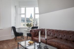 a living room with a brown leather couch and chairs at Sudurgata - Luxury Dream Apartment in Reykjavík