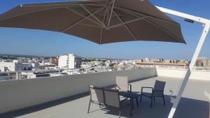 d'une table et de chaises sur un balcon avec un parasol dans l'établissement Penthouse Salento - Galatina, à Galatina