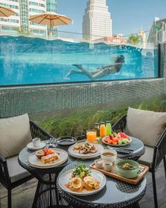 een tafel met borden eten naast een zwembad bij Tastoria Collection Sukhumvit - SHA Extra Plus in Bangkok