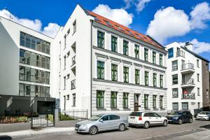 un bâtiment blanc avec des voitures garées devant lui dans l'établissement Old Town LTC - Apartments Starówka Panieńska, à Gdańsk