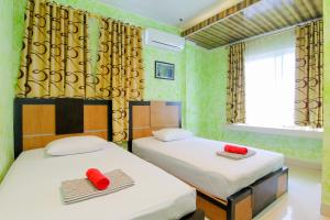 two beds in a room with two red pillows at Yani Homestay in Padang