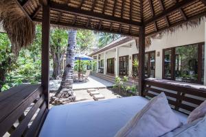 ein Schlafzimmer im Freien mit einem Bett und einem Baum in der Unterkunft Rumah Antony in Gili Trawangan