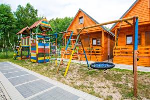 a playground with colorful play equipment in front of houses at Domki KARO in Rowy