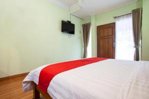 a bedroom with a red and white bed and a television at RedDoorz near Juanda International Airport in Surabaya