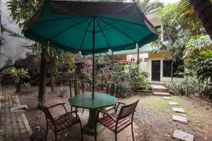 a table and chairs with a green table and an umbrella at RedDoorz near Juanda International Airport in Surabaya