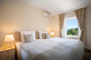 a bedroom with a large white bed with a window at Apartments Belvedere - by Liburnia Hotels & Villas in Lovran