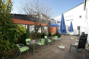 un patio avec des chaises, des tables et des parasols dans l'établissement Hotel am Baronenwald, à Göppingen