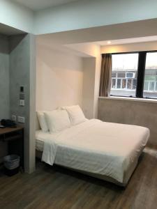 a bedroom with a bed with white sheets and a window at Homy Central in Hong Kong