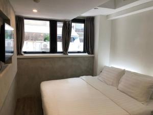 a white bed in a room with windows at Homy Central in Hong Kong