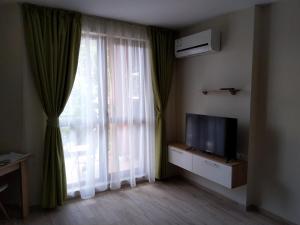 ein Wohnzimmer mit einem TV und einem Fenster in der Unterkunft Cascadas Ravda Apartment in Rawda
