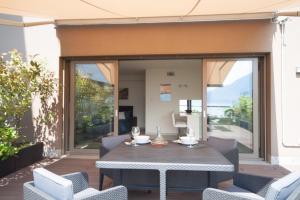 un patio con puertas de cristal, mesa de comedor y sillas en Terrazza sul Lago en Acquaseria