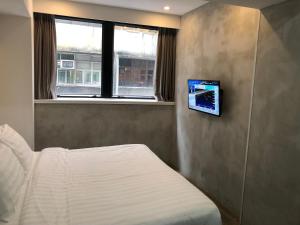 a bedroom with a bed and a tv on the wall at Homy Central in Hong Kong