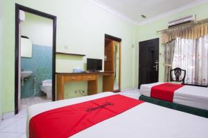 a hotel room with two beds and a bathroom at RedDoorz near Juanda International Airport in Surabaya